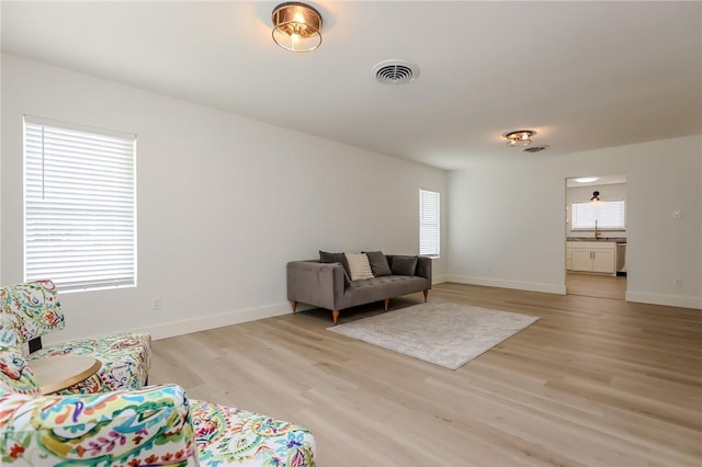 living room with baseboards, a wealth of natural light, light wood finished floors, and visible vents