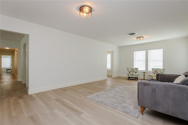 living room with light wood-style floors, baseboards, and visible vents