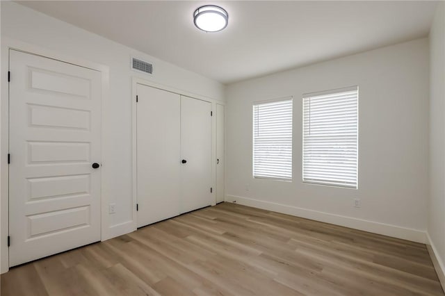 unfurnished bedroom featuring visible vents, baseboards, a closet, and light wood-type flooring