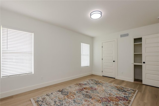 bedroom featuring baseboards, light wood-style flooring, and visible vents
