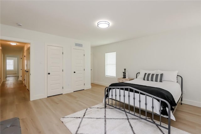 bedroom with visible vents, light wood-style flooring, and baseboards