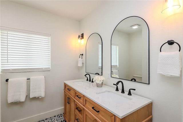full bath with a sink, baseboards, and double vanity