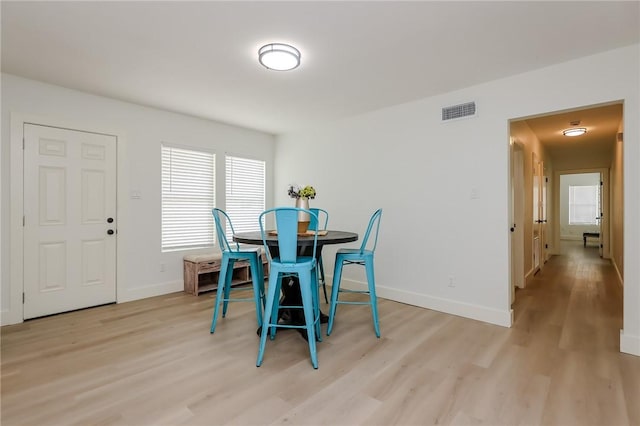 dining area featuring baseboards, light wood finished floors, and visible vents