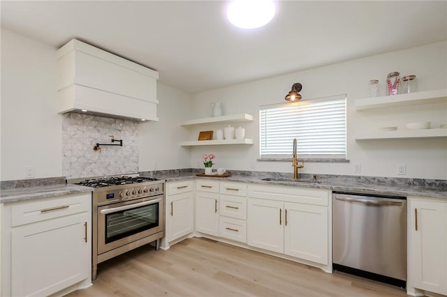 kitchen with open shelves, a sink, light wood-style flooring, premium range hood, and stainless steel appliances