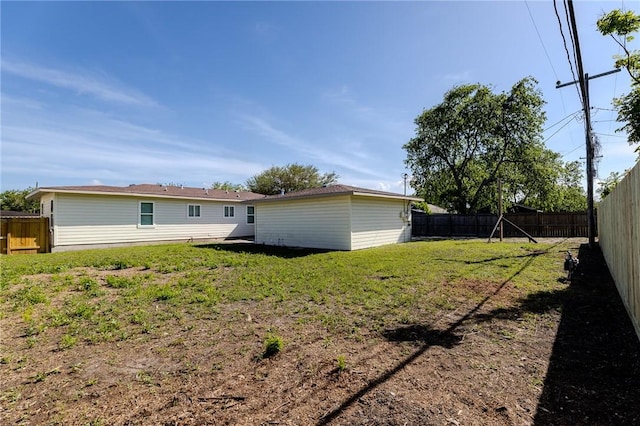 back of house with a fenced backyard and a lawn