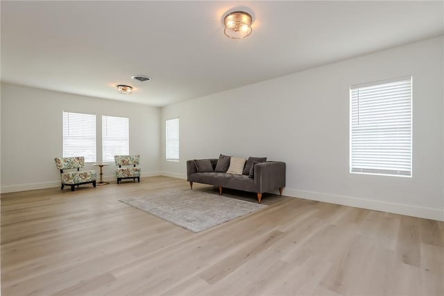 living room featuring light wood-style floors, baseboards, and visible vents