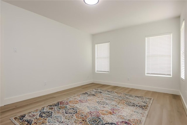 empty room featuring a healthy amount of sunlight, baseboards, and light wood-style flooring