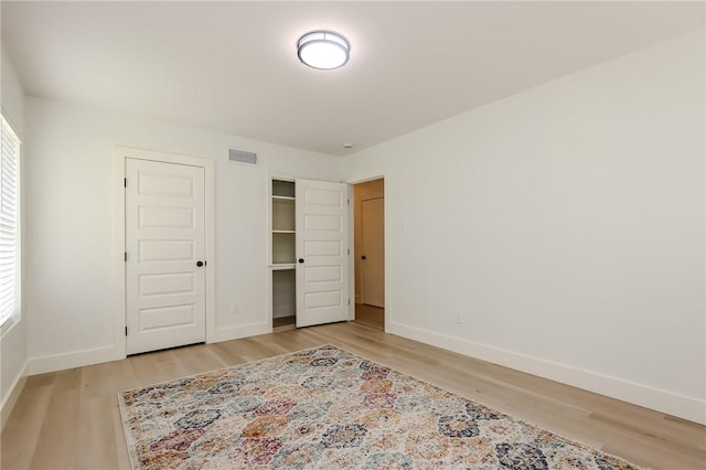 bedroom with light wood-type flooring, baseboards, and visible vents