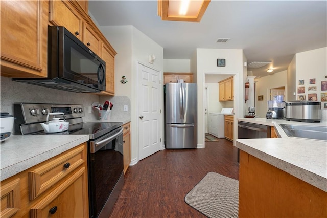 kitchen featuring sink, stainless steel appliances, tasteful backsplash, washing machine and dryer, and dark hardwood / wood-style flooring