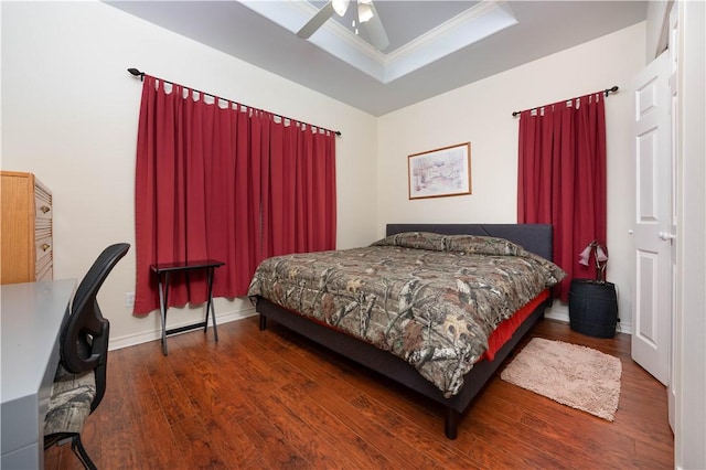 bedroom with dark hardwood / wood-style flooring, a tray ceiling, ceiling fan, and crown molding