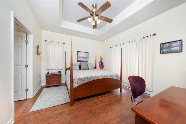 bedroom featuring hardwood / wood-style floors, ceiling fan, ornamental molding, and a tray ceiling