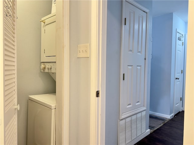 laundry area featuring dark hardwood / wood-style flooring and stacked washer and dryer