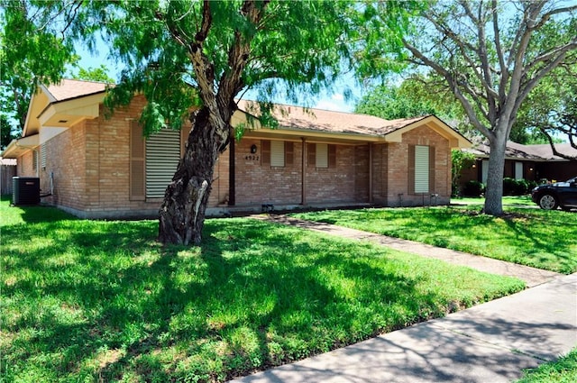 view of front of house featuring brick siding, a front yard, and central AC unit