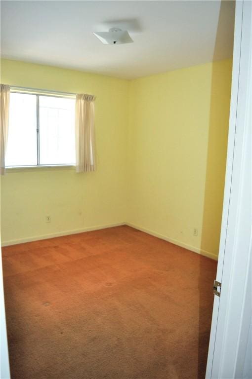 spare room featuring carpet floors and baseboards