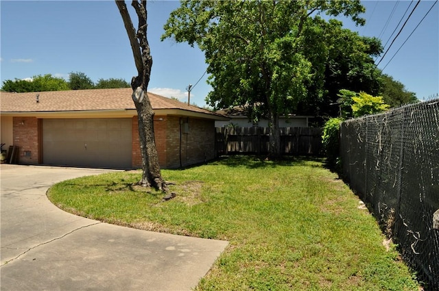 view of yard featuring an attached garage and concrete driveway