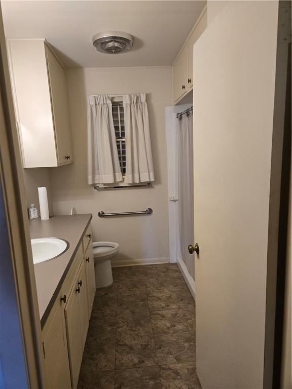 full bathroom featuring toilet, vanity, and baseboards