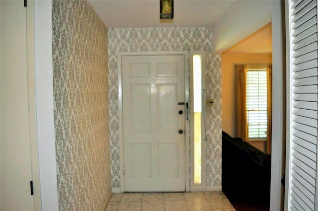 foyer featuring wallpapered walls, baseboards, and light tile patterned flooring