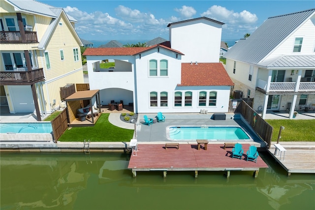 rear view of house featuring a patio, a water view, a lawn, and a balcony