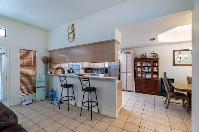 705 Aurora St, Bishop, TX 78343 - kitchen with stainless steel fridge with ice dispenser, a peninsula, light tile patterned flooring, a chandelier, and a breakfast bar area