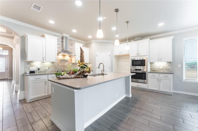 8233 Yosemite Dr, Corpus Christi, TX 78414 - kitchen with wall chimney exhaust hood, appliances with stainless steel finishes, a sink, wood tiled floors, and ornamental molding