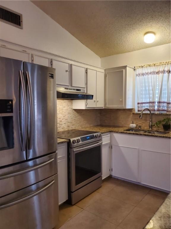 kitchen with light tile patterned floors, visible vents, decorative backsplash, stainless steel appliances, and under cabinet range hood