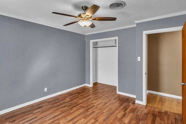 unfurnished bedroom featuring hardwood / wood-style flooring, ceiling fan, ornamental molding, and a closet