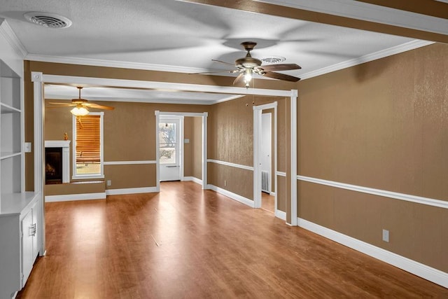 unfurnished living room featuring a textured ceiling, hardwood / wood-style flooring, ceiling fan, and ornamental molding