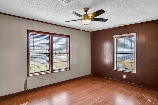 empty room with hardwood / wood-style flooring, ceiling fan, a textured ceiling, and wooden walls