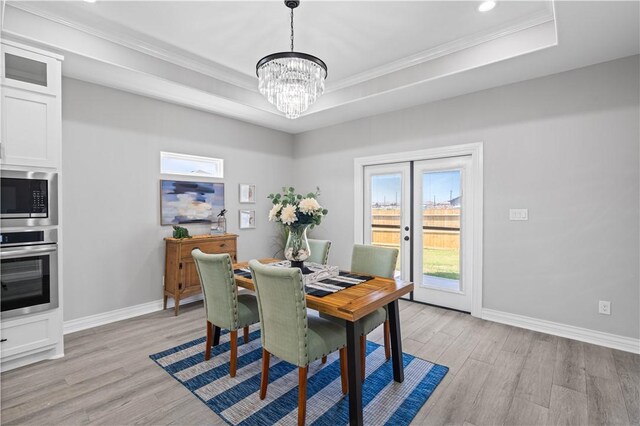 7721 Keiras Way, Corpus Christi, TX 78414 - dining room with light wood-style floors, a chandelier, a tray ceiling, baseboards, and ornamental molding