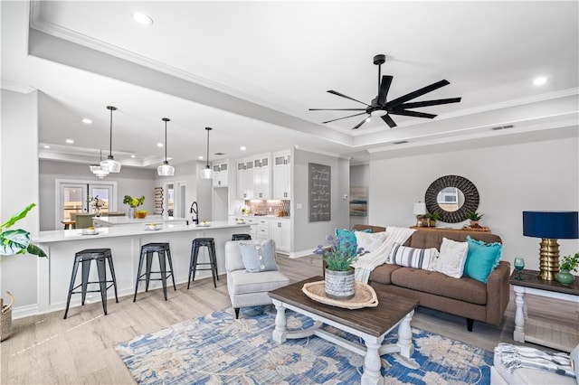 7721 Keiras Way, Corpus Christi, TX 78414 - living room with a raised ceiling, ornamental molding, light wood finished floors, recessed lighting, and a ceiling fan