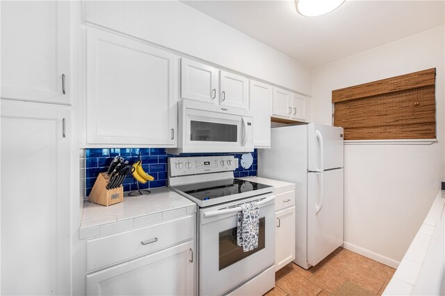 kitchen with white appliances, tile countertops, white cabinetry, and tasteful backsplash