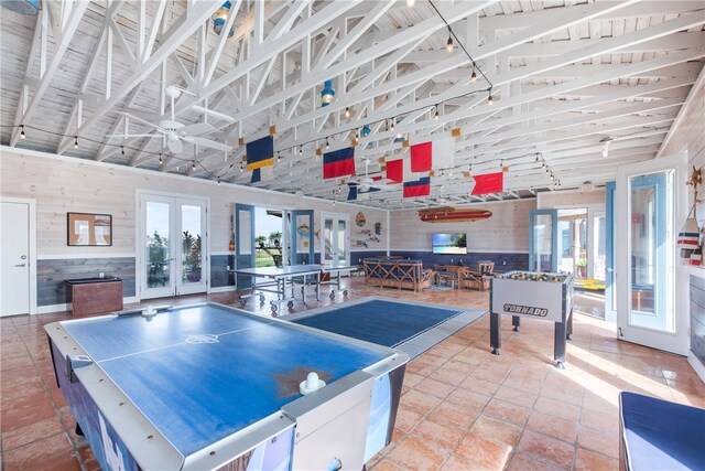 recreation room with french doors, beam ceiling, wooden walls, and high vaulted ceiling