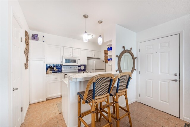 kitchen featuring white cabinetry, pendant lighting, white appliances, and decorative backsplash