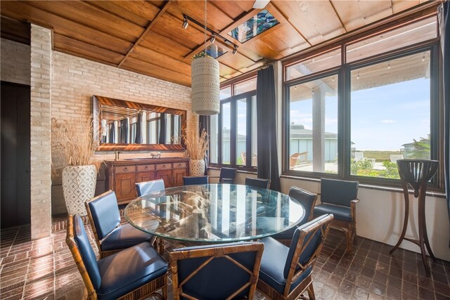 dining room featuring brick wall and wood ceiling