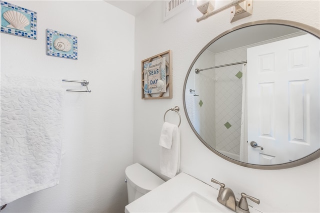 bathroom with tiled shower, sink, and toilet