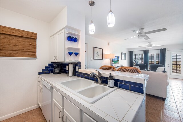 kitchen with light tile patterned floors, sink, white cabinets, dishwasher, and kitchen peninsula