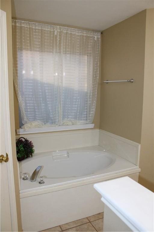 bathroom with tile patterned flooring and a tub