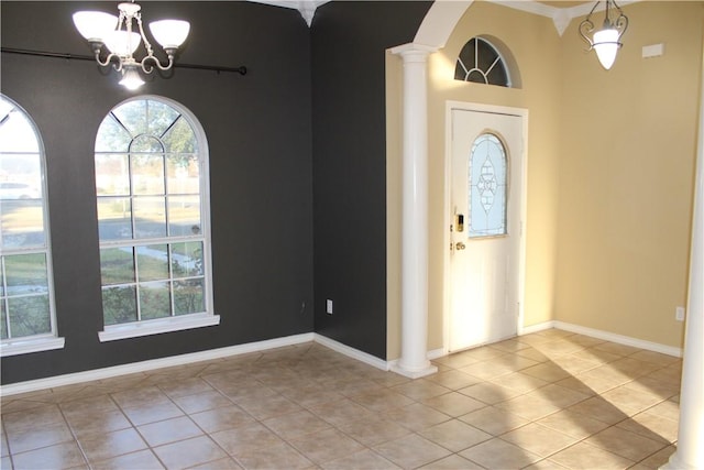 entryway with decorative columns, light tile patterned flooring, and a chandelier