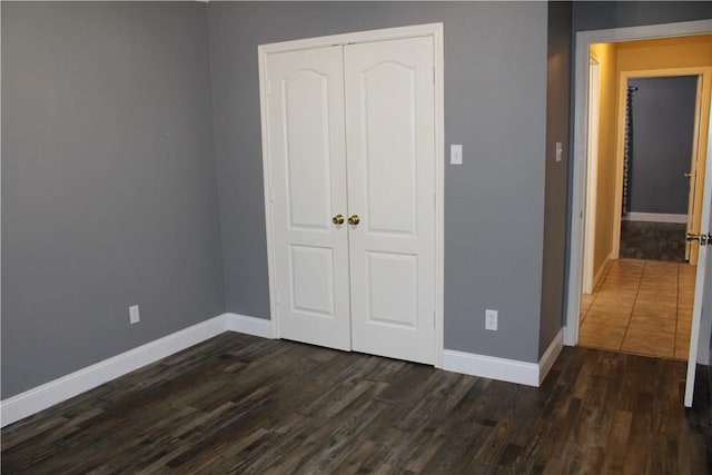 unfurnished bedroom featuring dark hardwood / wood-style flooring and a closet