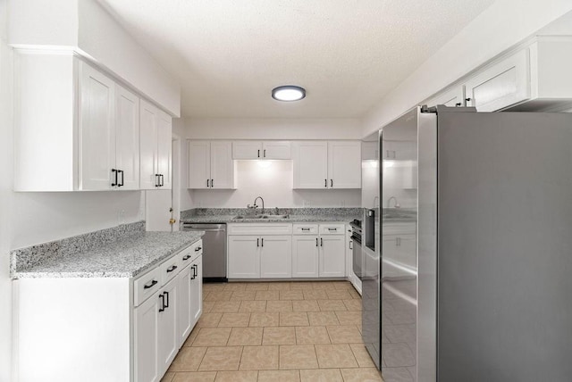 1134 Harbor Village Dr, Corpus Christi, TX 78412 - kitchen featuring stainless steel appliances, a sink, white cabinets, light stone countertops, and a textured ceiling