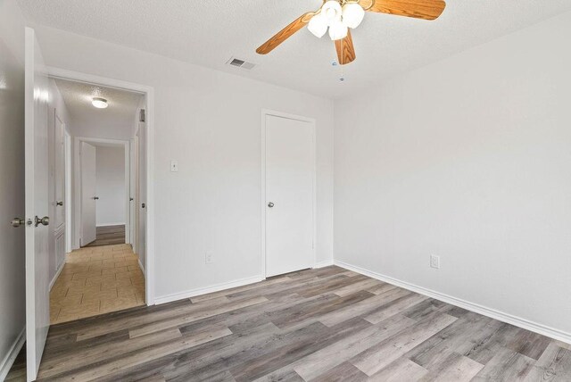 1134 Harbor Village Dr, Corpus Christi, TX 78412 - unfurnished bedroom featuring wood finished floors, baseboards, a textured ceiling, and a ceiling fan