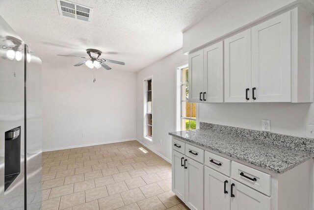 1134 Harbor Village Dr, Corpus Christi, TX 78412 - kitchen with a ceiling fan, a textured ceiling, white cabinetry, light stone counters, and baseboards