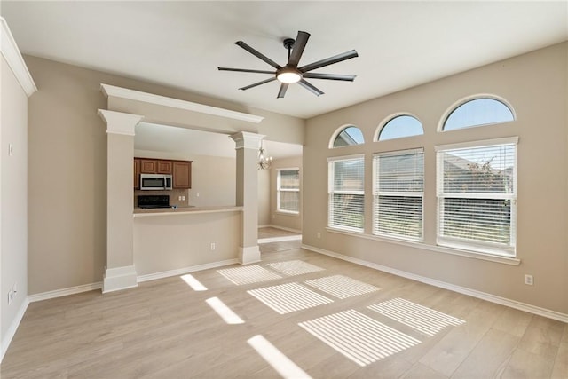 unfurnished living room with light wood-style flooring, baseboards, and ceiling fan with notable chandelier