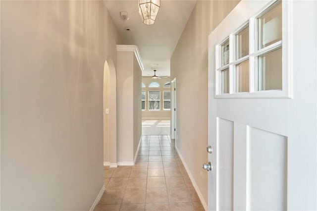 hall with light tile patterned floors, arched walkways, and baseboards