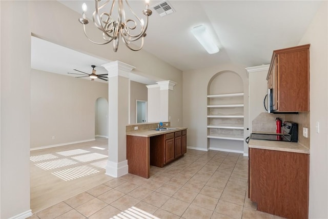 kitchen featuring light tile patterned floors, brown cabinetry, stove, light countertops, and ceiling fan with notable chandelier