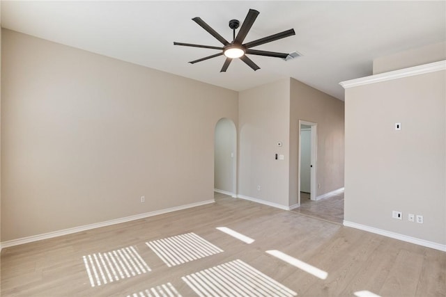 unfurnished room featuring light wood finished floors, ceiling fan, arched walkways, and baseboards