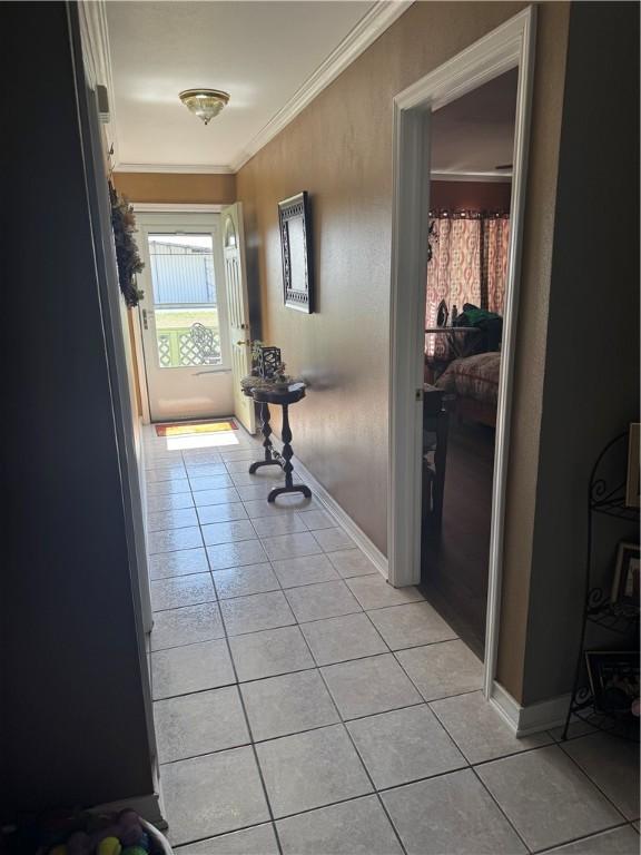 hallway with light tile patterned floors, baseboards, and ornamental molding