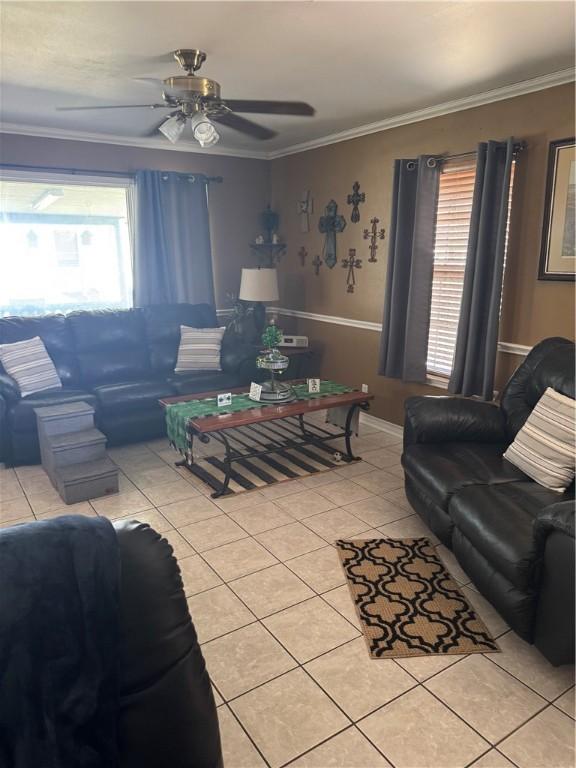 living area with light tile patterned floors, ornamental molding, and ceiling fan