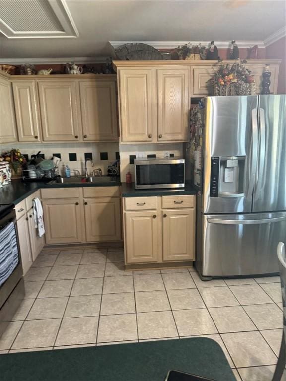 kitchen with dark countertops, appliances with stainless steel finishes, crown molding, and a sink