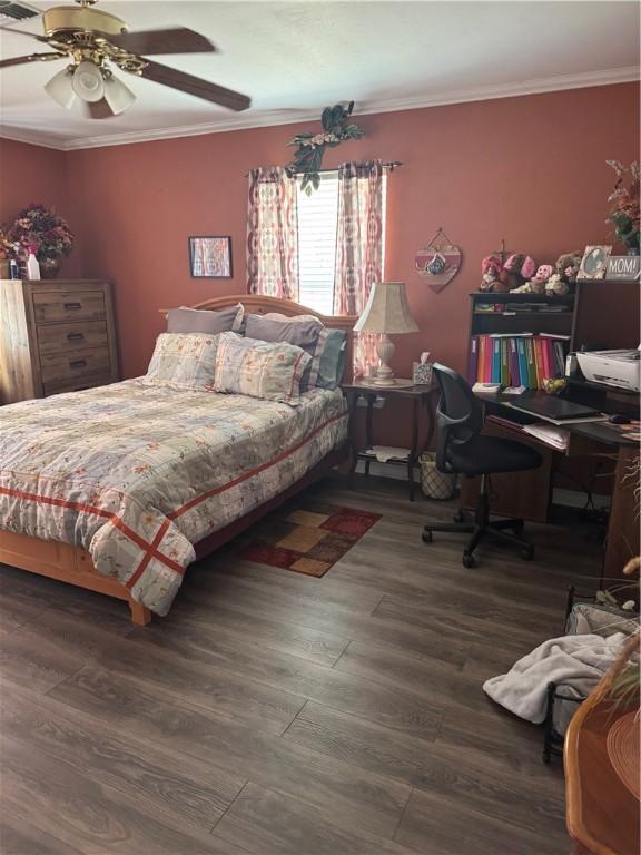 bedroom with a ceiling fan, wood finished floors, visible vents, and ornamental molding